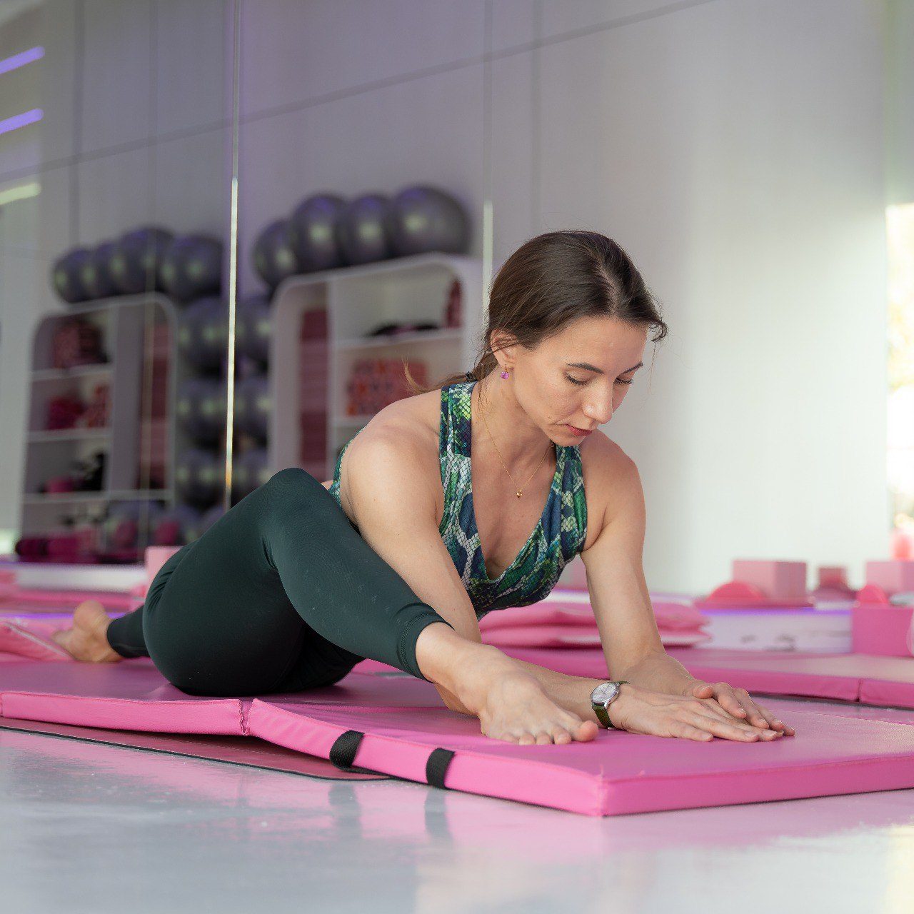 Radmila Aitova stretching forward over her legs on a mat during a session